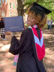 a young woman holds up her graduation plaque from Agnes Scott