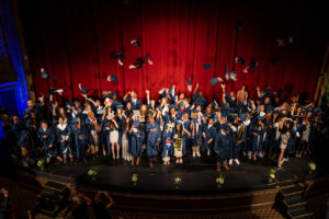 Students throw their grad caps in their air at graduation. 